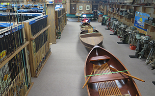 A museum aisle lined with wooden canoes, fishing rods and outboard motors on display