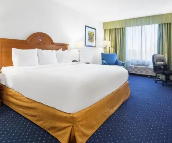 A king bed with an arched wooden headboard, a blue armchair and a desk
