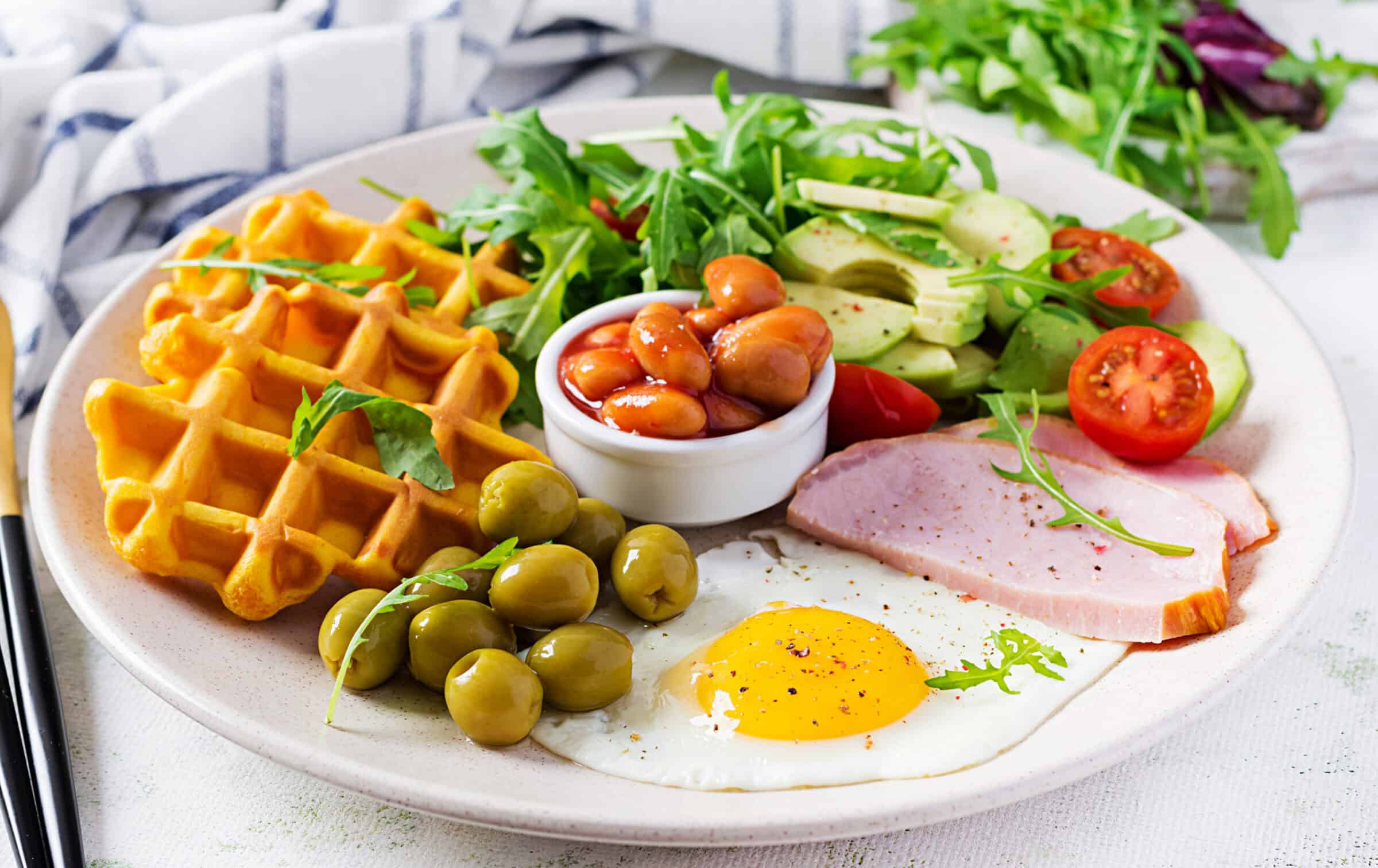 Breakfast plate with waffles fried egg ham and fresh vegetables representing breakfast variety near Highway 76 in Branson Missouri