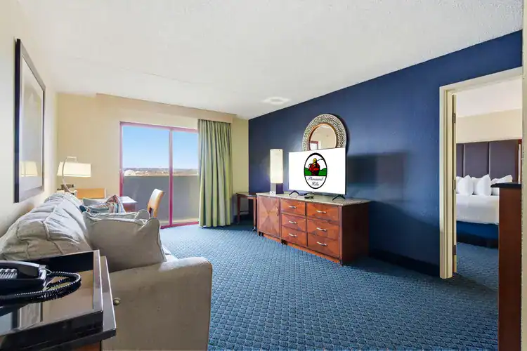 Renovated suite living area at Thousand Hills Resort Hotel in Branson with blue carpet, flatscreen TV, and separate bedroom