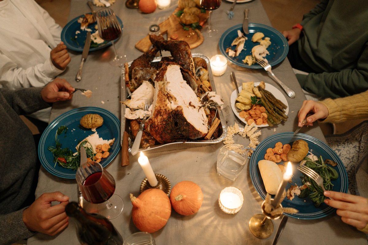 A table set for a meal with a large turkey, pumpkins, and candles.